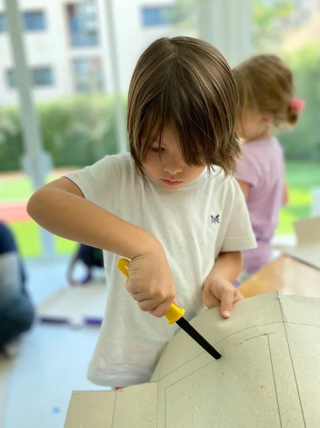 A boy cutting cardboard along the lines of his own design