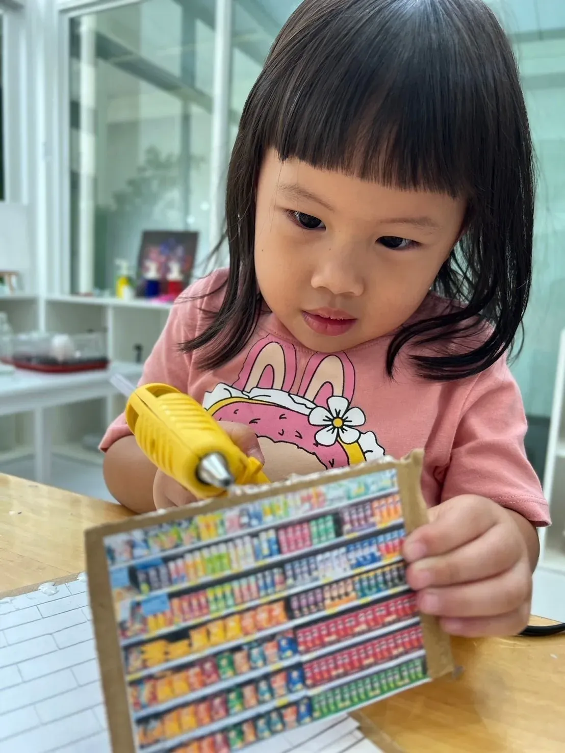 A girl gluing a printed shop shelf onto her cardboard model