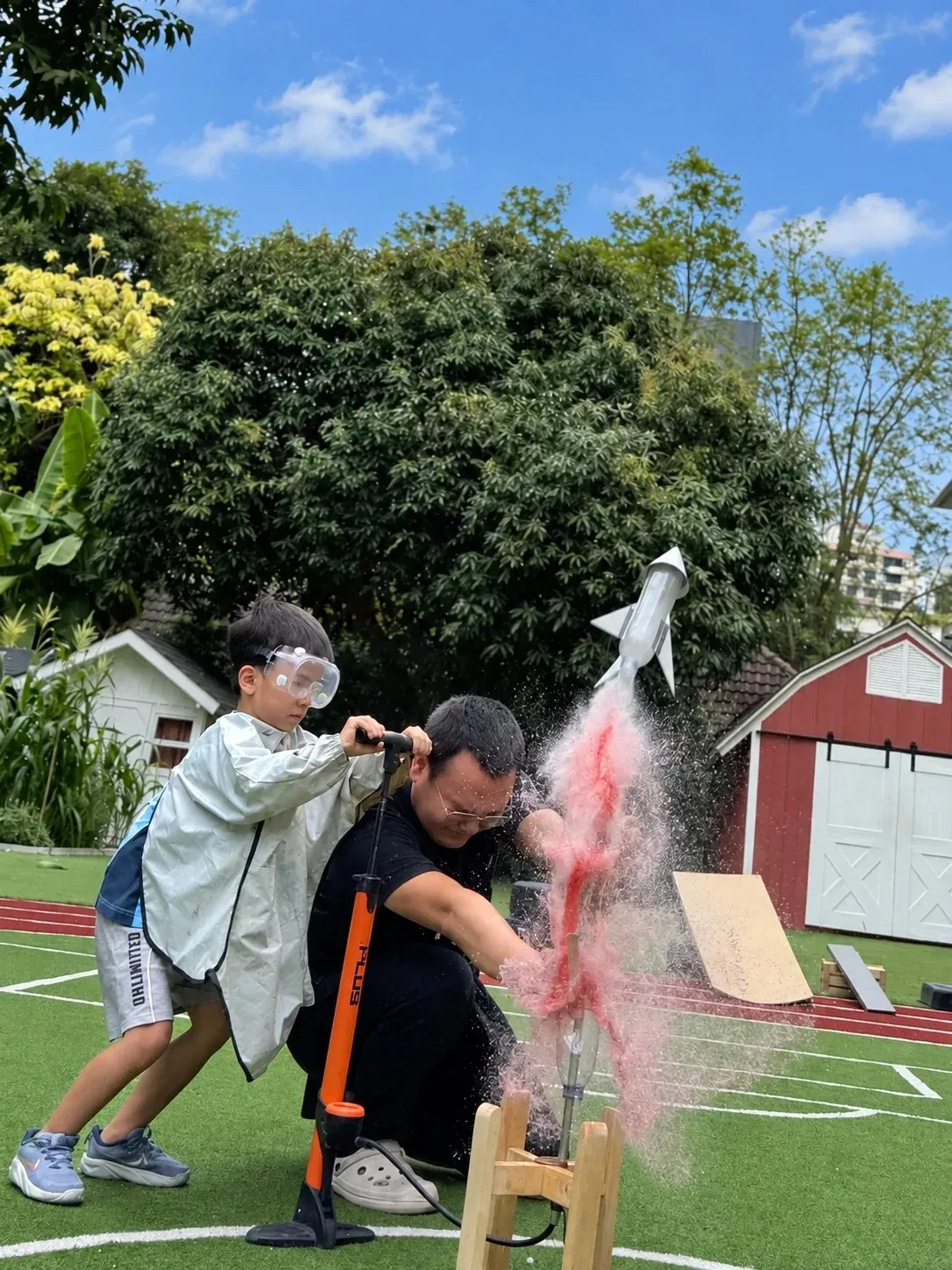 A boy in safety goggles pumping air to launch a water bottle rocket