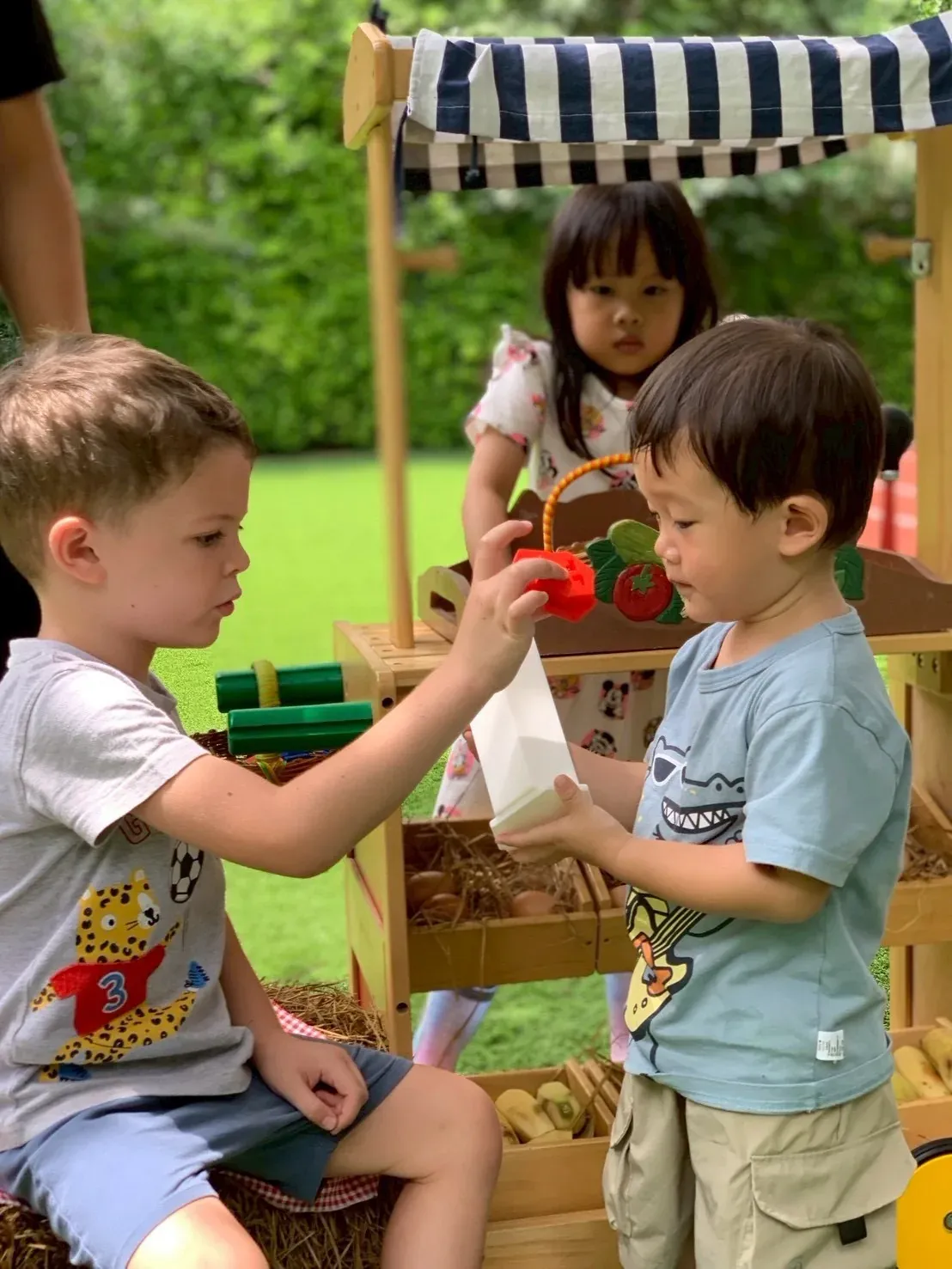A boy paying with a KIMS coin while a friend holds out his coin box
