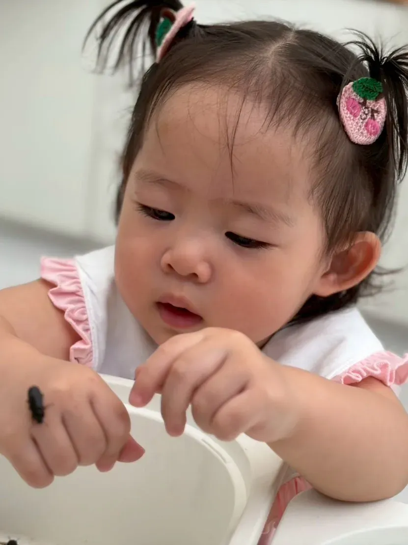 A toddler watching a beetle walk across her hand