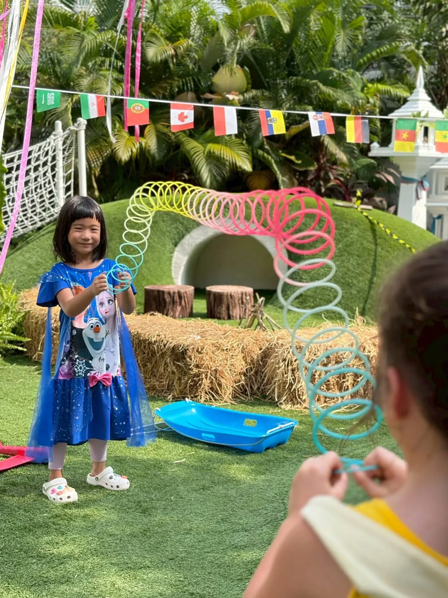 A girl stretching a rainbow spring across the garden with a friend