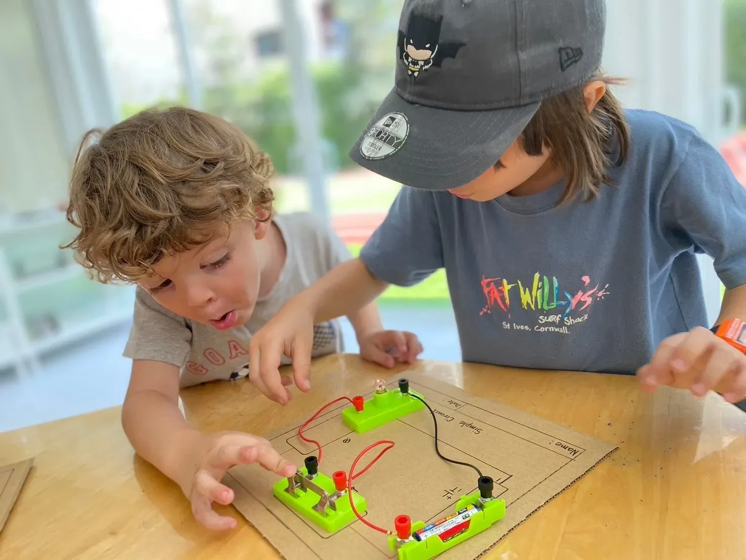 Two boys gasping as the bulb on their simple circuit lights up