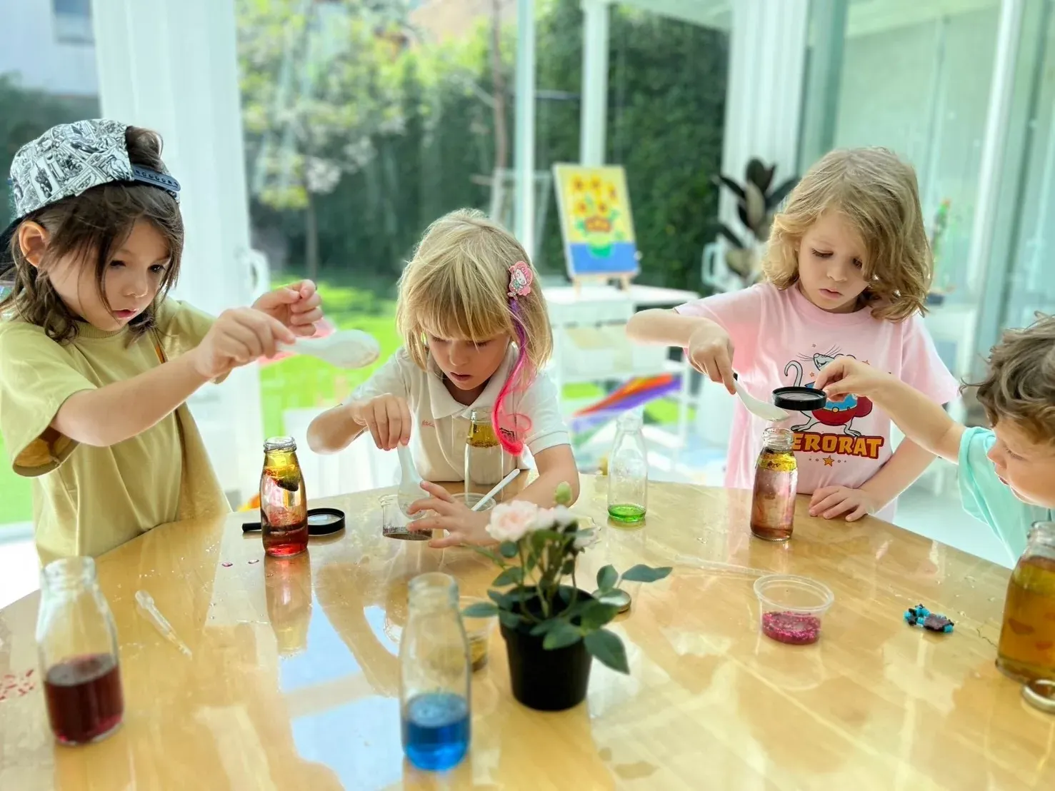 Four children spooning colours and oil into bottles to make their own lava lamps