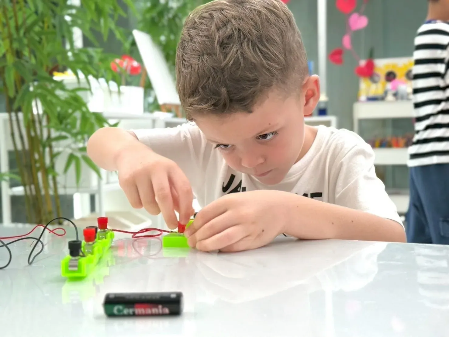 A boy concentrating as he wires up a simple electric circuit